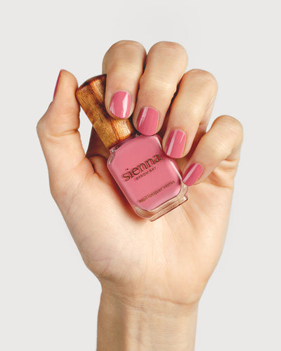 midtone pink nail polish hand swatch on fair skin tone holding a sienna bottle