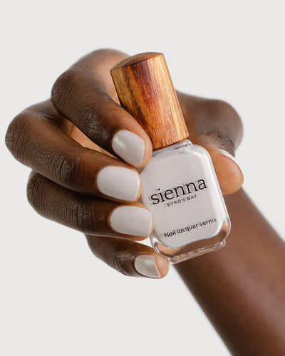 cool grey nail polish hand swatch on dark skin tone holding sienna bottle