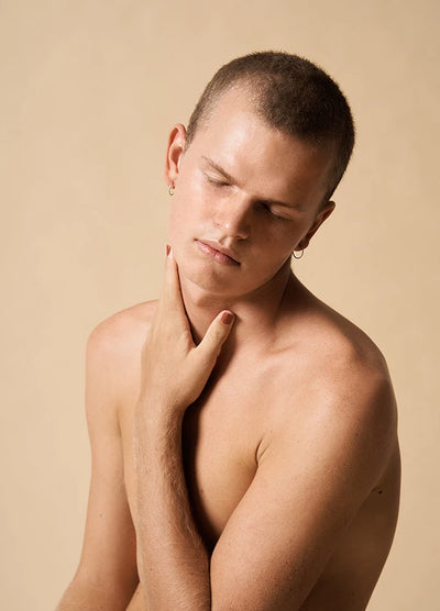 Fair skin man wearing Life Brick Red Crème non-toxic nail polish holding hand gently on neck