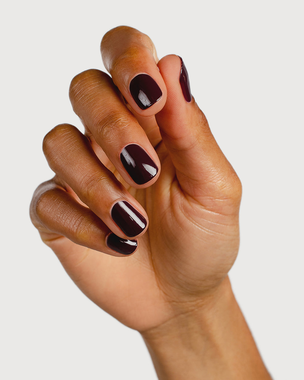 Aubergine nail polish hand swatch on medium skin tone