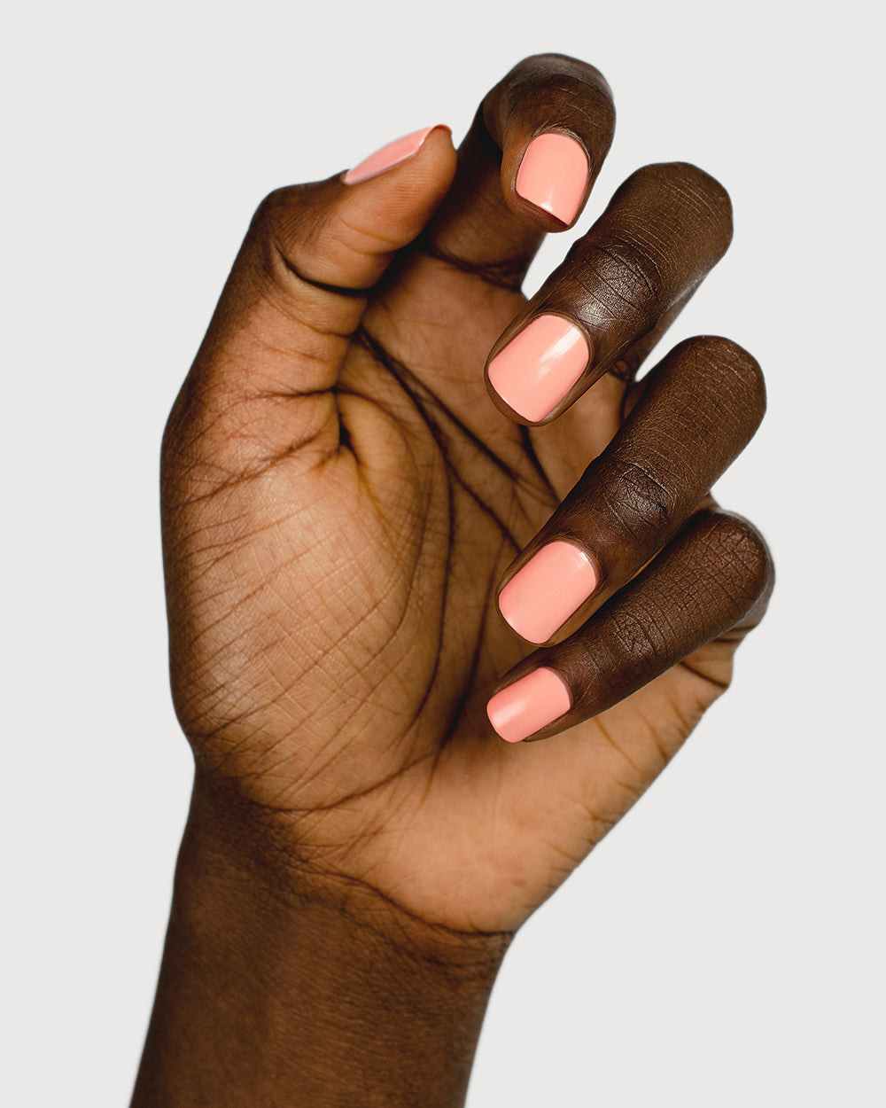 Vibrant peach nail polish hand swatch on dark skin tone
