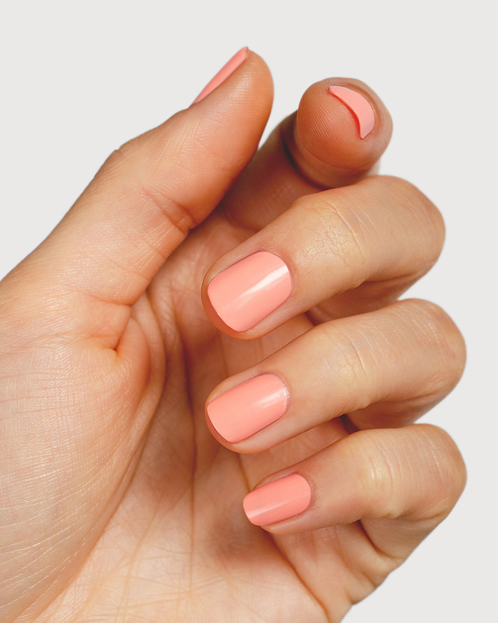 Vibrant peach nail polish hand swatch on fair skin tone