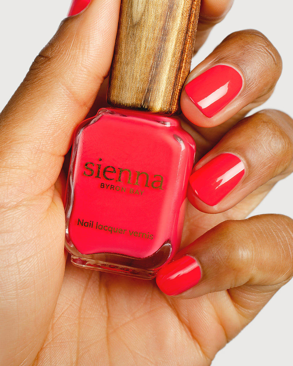 barbie pink nail polish hand swatch on medium skin tone holding sienna bottle up close