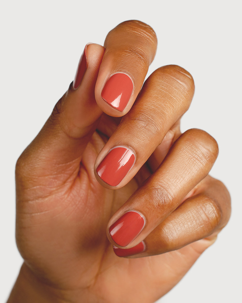 red brick nail polish hand swatch on medium skin tone up close