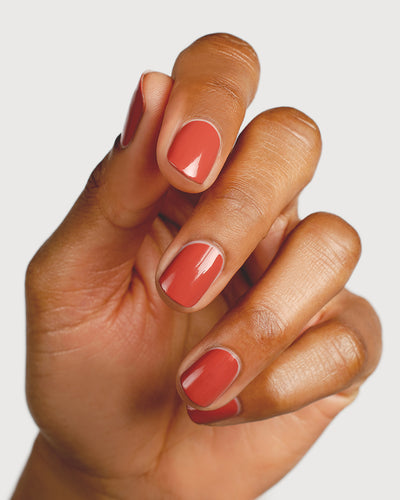 red brick nail polish hand swatch on medium skin tone up close