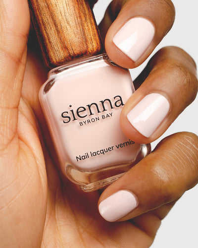 rosewater pink nail polish hand swatch on medium skin tone holding sienna bottle