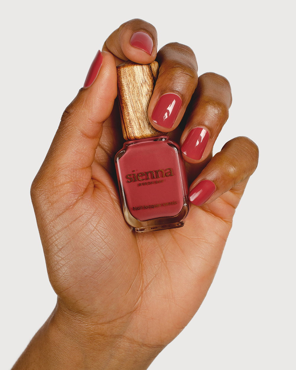 dusty rosebud nail polish hand swatch on medium skin tone holding sienna bottle