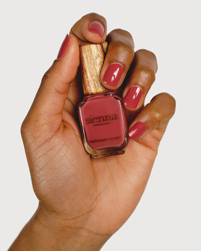 dusty rosebud nail polish hand swatch on medium skin tone holding sienna bottle