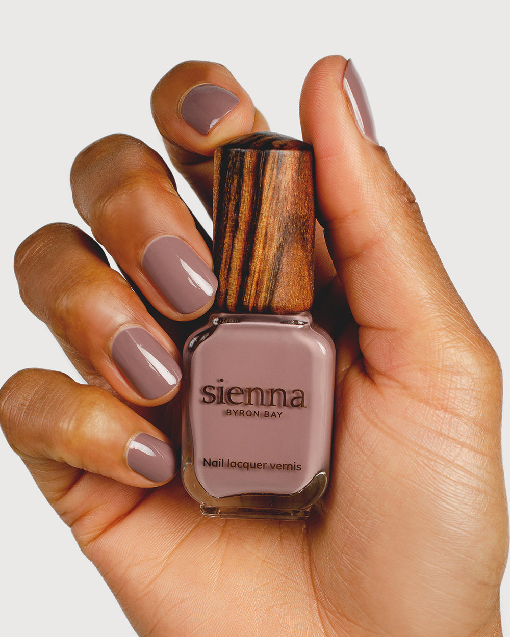 dusty mauve nail polish hand swatch on medium skin tone holding sienna bottle