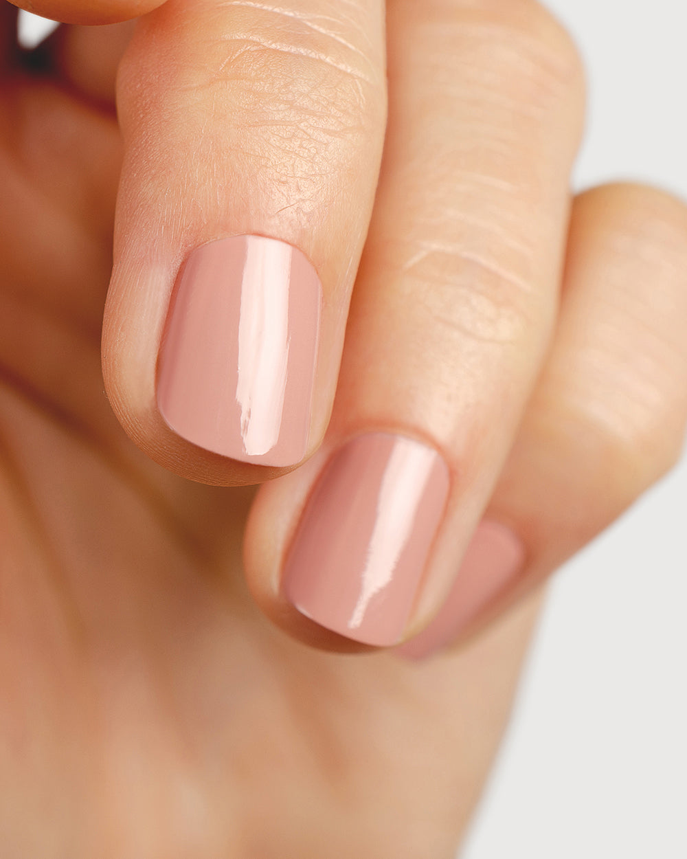 Dusty rose nail polish hand swatch on fair skin tone close-up