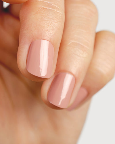 Dusty rose nail polish hand swatch on fair skin tone close-up