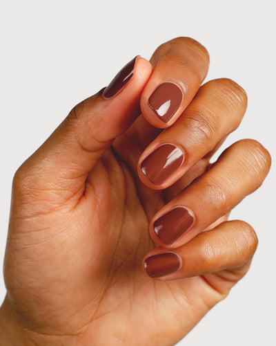 Deep burnt umber nail polish hand swatch on medium skin tone close-up