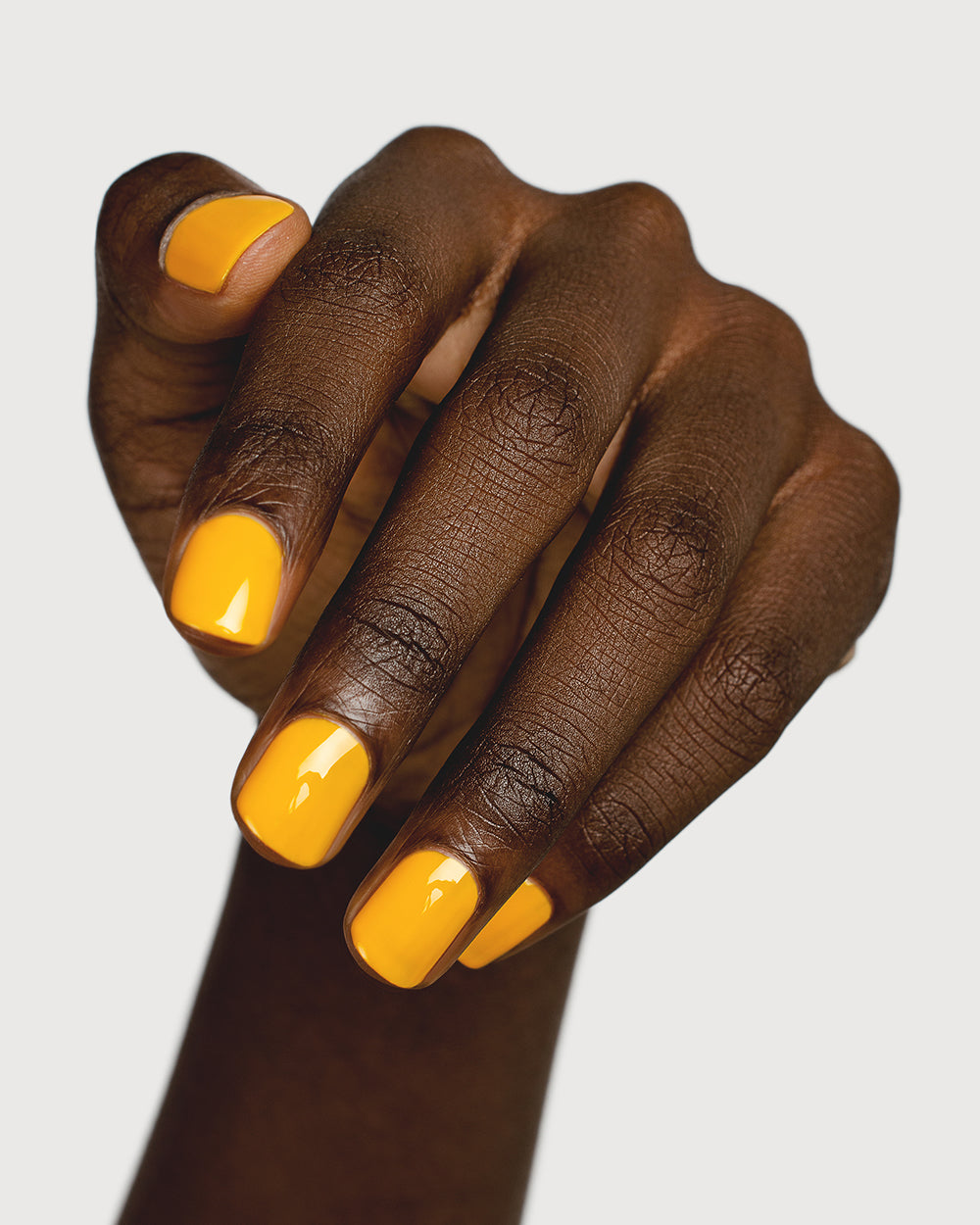 Sunflower yellow nail polish hand swatch on dark skin tone