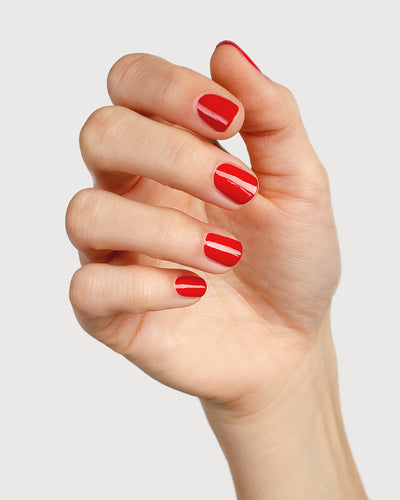 Classic red nail polish hand swatch on fair skin tone