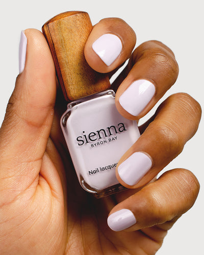 Light lilac pastel nail polish hand swatch on medium skin tone up close holding sienna bottle